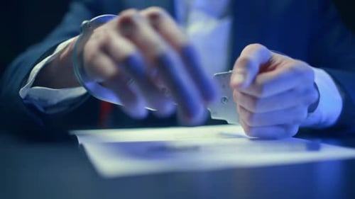 Handcuffed Person Signing Document