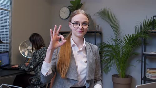 Young Woman Gives Okay Sign in Modern Office