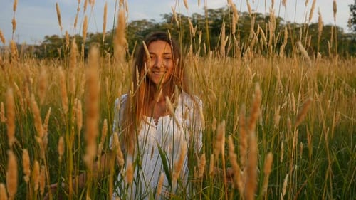 Woman Walks Through Golden Wheat Field at Sunset