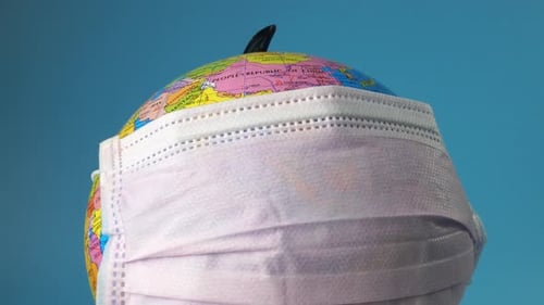 Globe Wearing Surgical Mask Against Blue Background