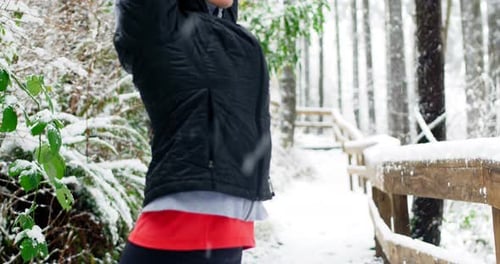Woman Stretching Arms in Snowy Winter Forest