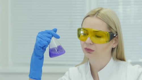Female Scientist Examines Purple Liquid in Flask