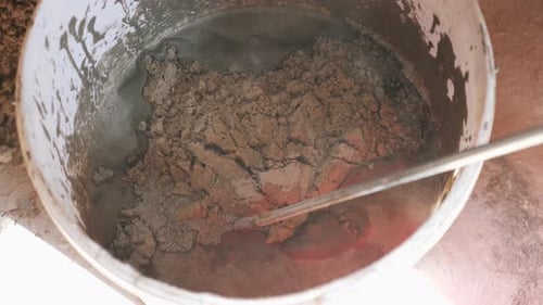 Adding Sand to a Construction Mix in a Bucket