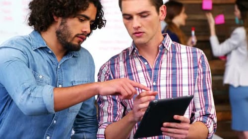 Young Adults Collaborate Using Tablet in Modern Office