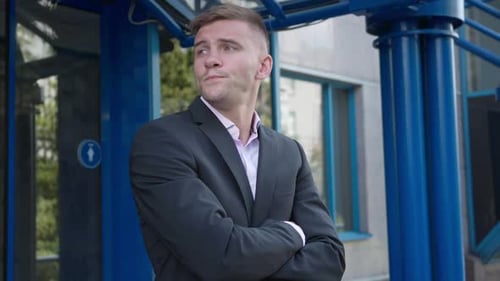 Handsome Caucasian Man in Suit with Crossed Hands Standing at Business Center Entrance Waiting