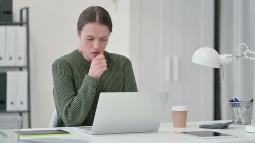 Woman Coughs at Desk While Working on Laptop