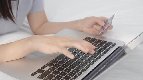 Woman's hands typing on a laptop holding credit card