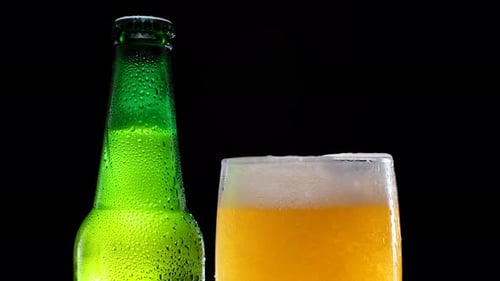 Refreshing Beer Pours into Glass Bottle Close Up