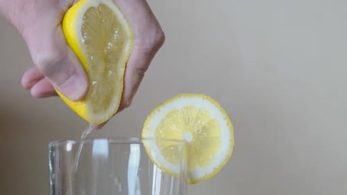 Hand Squeezing Lemon Juice into Glass