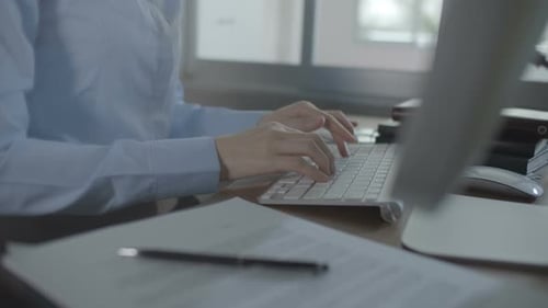 Woman Typing on Keyboard at Desk in Office