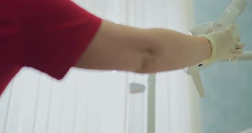 Dentist Adjusting Examination Light for Young Adult Patient