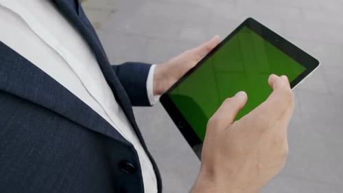 Businessman Browsing Internet on Tablet Outdoors. Male Hands Typing on Pad