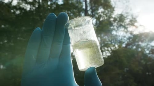 Chemist in Ppe Looking at Flask with Solution Water Analysis From Swamp Wearing Protective Suit and