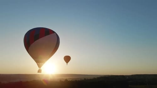 Hot Air Balloons Float Over Countryside at Sunset