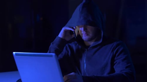 Hooded Person Working at a Laptop at Night