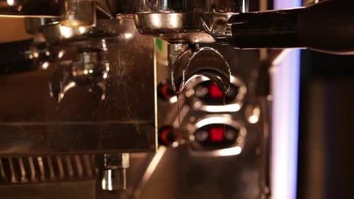 Pouring coffee stream from professional machine in cup. Flowing fresh ground coffee.