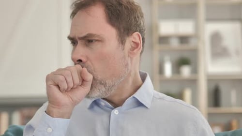 Adult Man Coughing into Fist Indoors Close Up