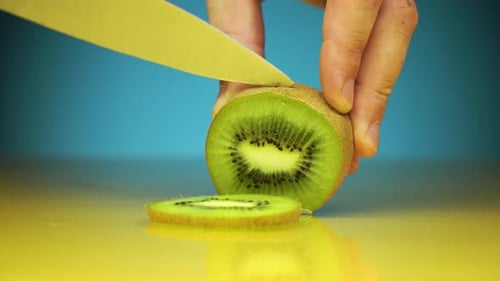 Knife Cutting Kiwi into Slices Close Up