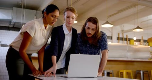 Diverse Team Collaborating on Laptop in Bright Workplace
