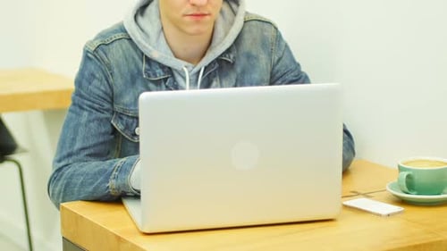 Mann benutzt Laptop beim Kaffeetrinken