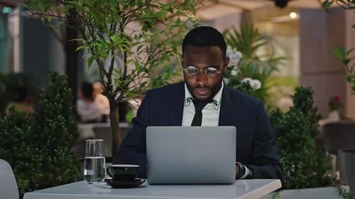 Busy African American Employee Wearing Eyeglasses Working on Laptop During Break Sitting at Outdoor