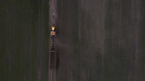 Luftaufnahme eines modernen gelben Traktors, der über das Feld fährt
