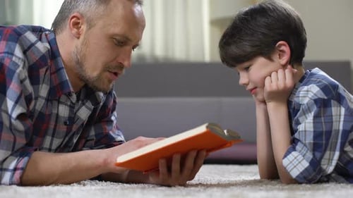 Father Reads to Son Lying on Carpet