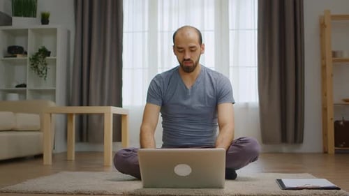 Man Using Laptop Sitting Cross-Legged on Rug