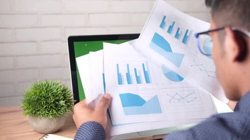 Rear View of Young Man Analyzing Bar Chart on Paper