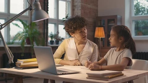 Woman Helping Child with Homework at Desk