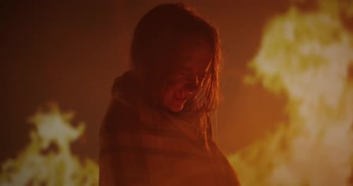 Woman Silhouetted by Fiery Light in the Darkness