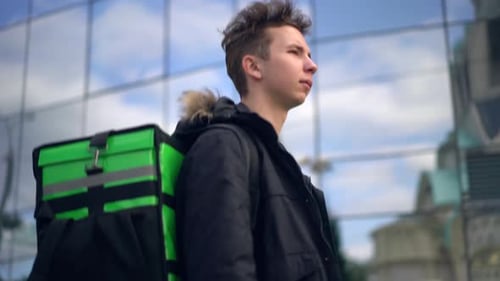 Livreur avec sac à dos vert se promène dans la ville avec livraison de nourriture