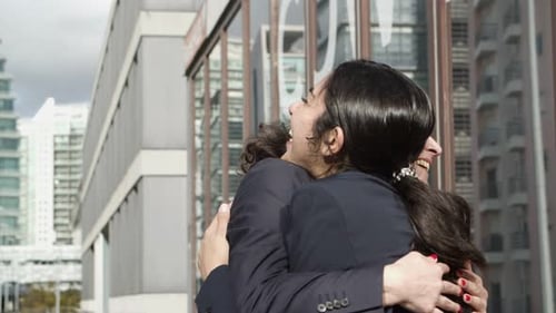 Businesswomen Embrace and Chat in Urban Setting