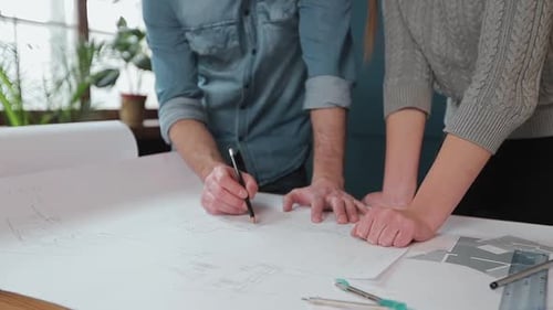 Close Up Hands of Two Workers Discussing Building Drawings in Office. Closeup Shooting of Arms