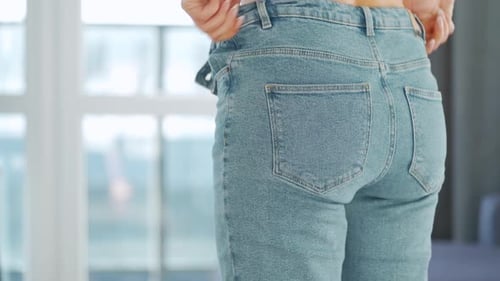 Woman Pulls Up Jeans Indoors by Window