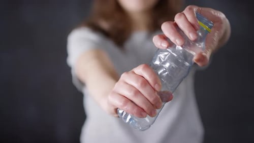 Woman Crushing a Clear Plastic Bottle with Hands
