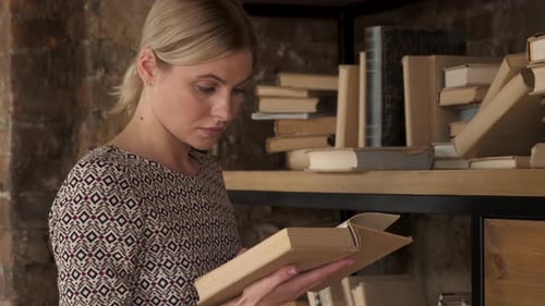 Close up of the Caucasian young beautiful woman student in glasses reading a book