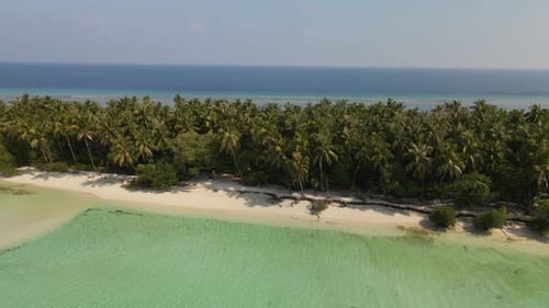 Panorama of a green island surrounded by water with yellow sand and a beach.
