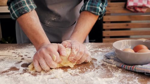 Person Kneading Dough on Floured Table in Kitchen