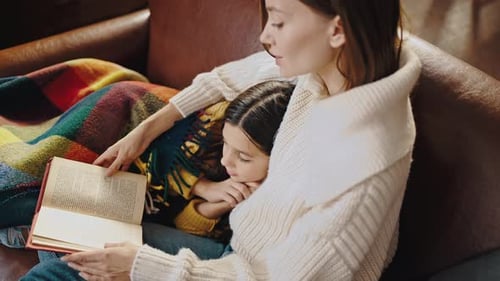 Woman and Child Reading Book on Couch