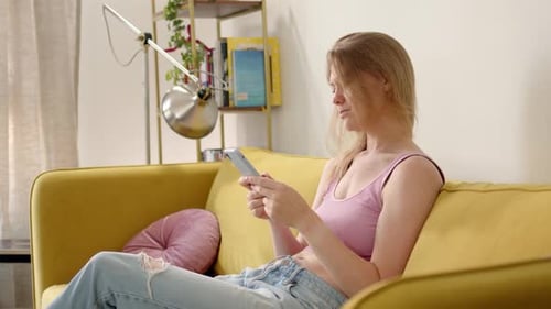 Woman Relaxing on Couch Using Smartphone Indoors