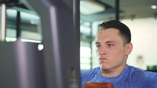 Young Man Exercising in the Gym on Machine