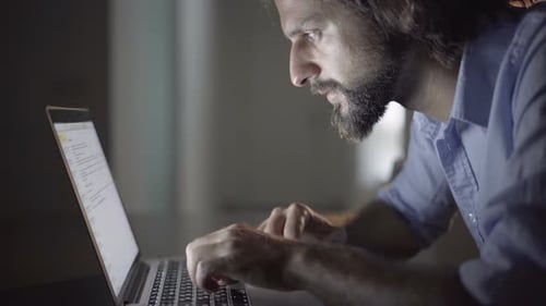Man Typing on Laptop Computer at Night