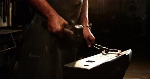 Blacksmith Shaping Hot Horseshoe with Hammer on Anvil
