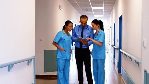 Medical Team Consults Over Tablet in Hospital Hallway