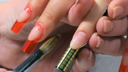 Manicurist Applying Acrylic Nail To Woman's Nails