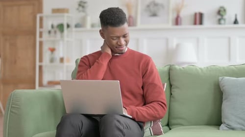 Man On Couch Experiences Neck Pain From Laptop