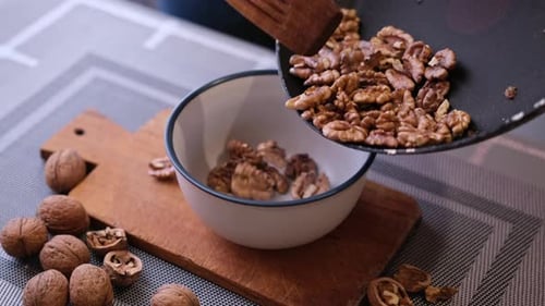 Pouring Walnuts Into Bowl In Bright Kitchen