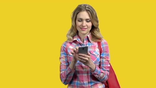 Woman Using Smartphone on Yellow Background