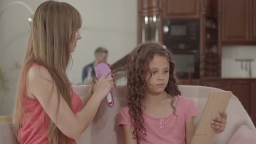 Mother Brushes Daughter's Curly Hair at Home